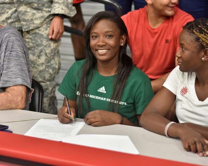 Linda Eloundou, with twin sister Manuella to her left, signs a letter of intent to play tennis for Eastern Michigan University. (NMMI Sports Press Photo)