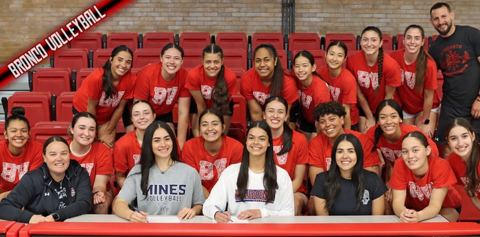 Surrounded by their teammates and coaches, Bronco volleyball sophomores Kekililani Helekahi (grey shirt) and Adriana de Jesus (white shirt) get ready to sign their Letters of Intent to play at the next level. (NMMI Sports Press photo)